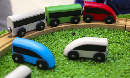 Children's wooden train with cars, railway and wooden trees on artificial plastic green grass.の写真素材