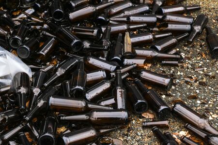 whole and broken brown bottles are scattered on the gravel.Concept: waste recycling, disposal of garbageの写真素材