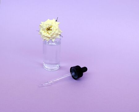 Glass bottle with oil or serum pipette, with small white rose flower on delicate background. Concept: organic bio cosmetics, vegetable oils, serum collagen, skin careの写真素材