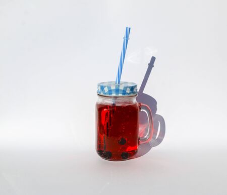 summer berry lemonade in a glass jar-mug with a lid and a straw on a white background.の写真素材