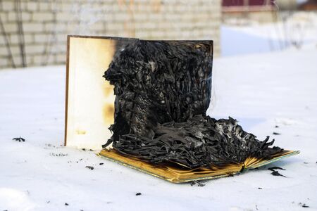 burning book in the snow. pages with the text in the open book burn with a bright flame.の写真素材