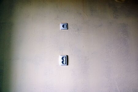 electrical outlets and switches made of white plastic on the wall in the room of an apartment or office, during repair.の写真素材