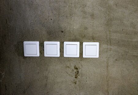 electrical outlets and switches made of white plastic on the wall in the room of an apartment or office, during repair.の写真素材