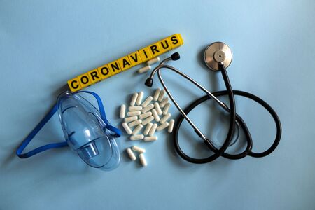 pills, stethoscope, thermometer, inhalation mask on a blue background with children`s yellow letters. Coronavirus 2019-nCoV disease and treatment concept.の写真素材