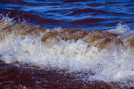 waves run onto the shore and crash against the rocks, creating many splashes and splashes near the...