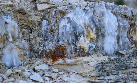 Diverse colored quartz rock in cut of earth. Deposits of gray, white, orange quartz. Untreated...