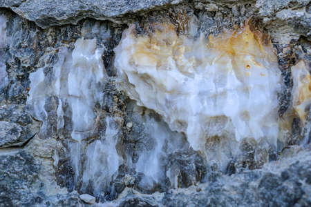 Diverse colored quartz rock in cut of earth. Deposits of gray, white, orange quartz. Untreated...