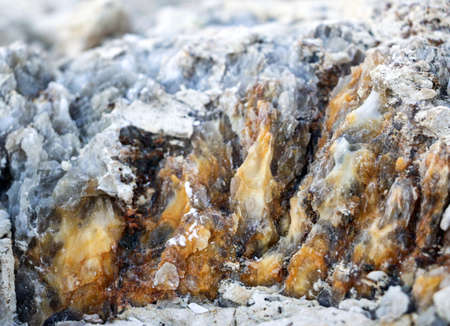 Diverse colored quartz rock in cut of earth. Deposits of gray, white, orange quartz. Untreated semi-precious stones of the chalcedony variety in various stone deposits and layers of different rocks.の写真素材