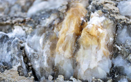 Diverse colored quartz rock in cut of earth. Deposits of gray, white, orange quartz. Untreated semi-precious stones of the chalcedony variety in various stone deposits and layers of different rocks.の写真素材