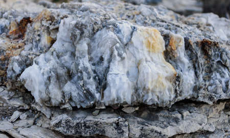 Diverse colored quartz rock in cut of earth. Deposits of gray, white, orange quartz. Untreated...