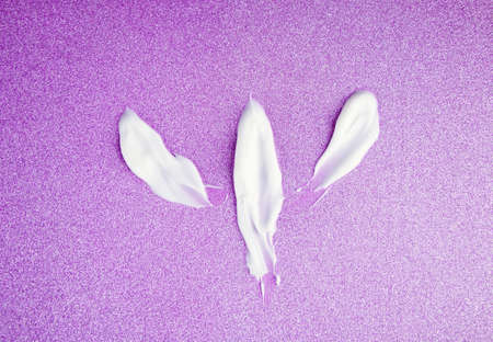 Drawing painted on textured strokes of white cream for skin care and moisturizing, on a shiny pink...