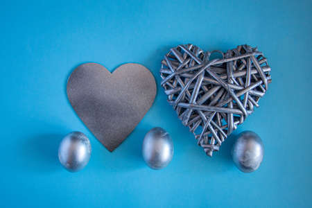 Silver eggs and a decorative silver heart on a delicate blue background. concept of rich Easter...