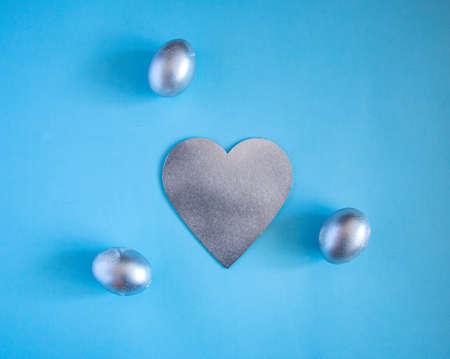 Silver eggs and a decorative silver heart on a delicate blue background. concept of rich Easter...