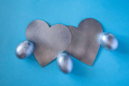 Silver eggs and a decorative silver heart on a delicate blue background. concept of rich Easter...