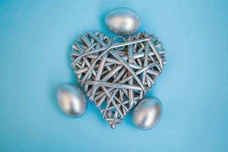 Silver eggs and a decorative silver heart on a delicate blue background. concept of rich Easter...