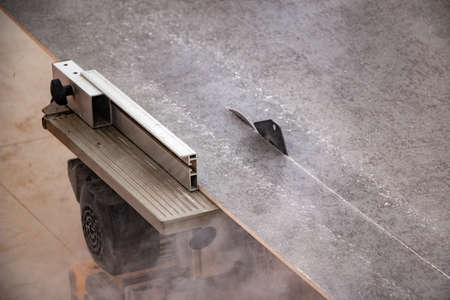 male hands of a construction worker sawing and cutting parts of an electric miter saw from a wooden...