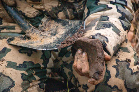 Male hands keep old iron fragments, clean them from dirt, clay, land and rust, after searching and...