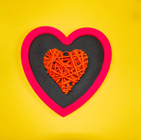 Wooden board for chalk inscriptions in the shape of a pink heart on a yellow background with various...