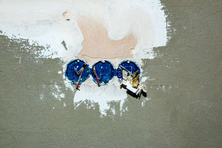 The opening for the outlet and switches in the plastered wall, with the tempered electrical wires,...