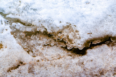 Cracks on thick ice on the surface of a frozen river in the winter season, powdered by snow and...