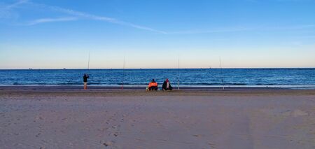 Fishermen with fishing rods on the beach of Punta Marina in Italyの写真素材