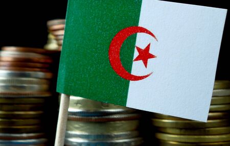 Algerian flag waving with stack of money coins macroの写真素材