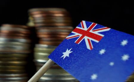 Australian flag waving with stack of money coins macroの写真素材