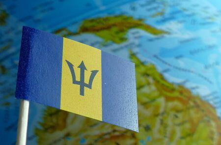 Barbados flag with a globe map as a background macroの写真素材