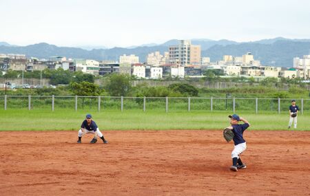 New Taipei City, Taiwan, May 18th 2011: Children  playing baseball in fieldのeditorial素材