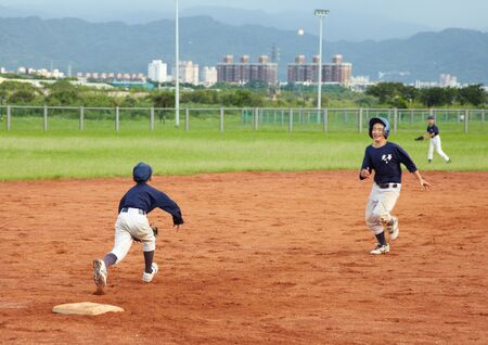 New Taipei City, Taiwan, May 18th 2011: Children  playing baseball in fieldのeditorial素材