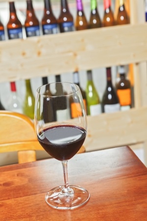 one glass of wine on woody table  and bottles as backgroundの写真素材