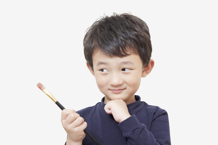 one asian boy child holds painting brush with white backgroundの写真素材