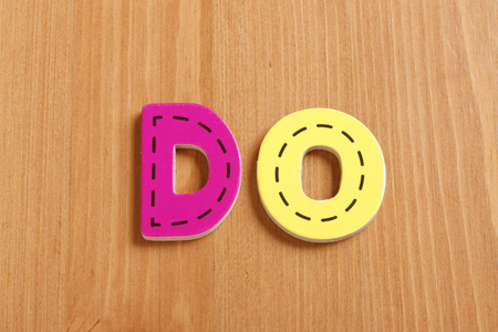 DO, spell by woody puzzle letters with woody backgroundの写真素材