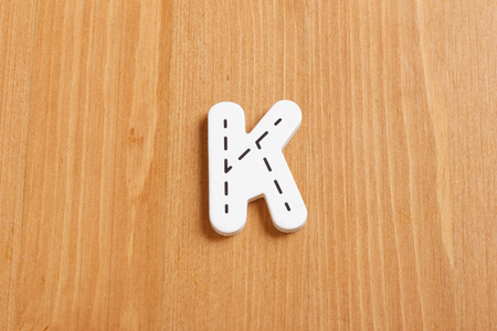 K, spell by woody puzzle letters with woody backgroundの写真素材