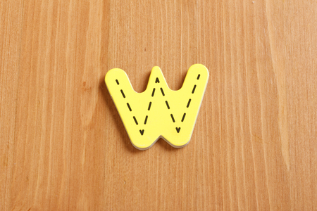W, spell by woody puzzle letters with woody backgroundの写真素材