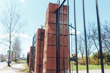 High fence with brick columns. Black Railings and brick wall.