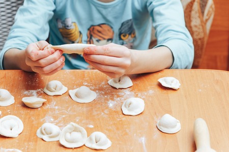 The girl is cooking dumplings at home in the kitchenの写真素材