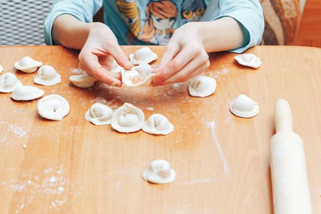 The girl is cooking dumplings at home in the kitchenの写真素材