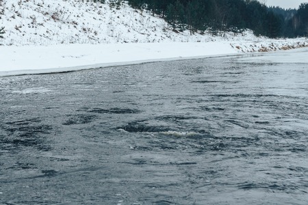 Boiling water in the river in the forest in winterの写真素材