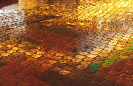 On the road from the tiles reflection of the lights of the storeの写真素材