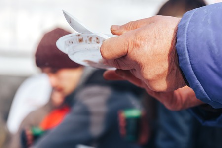 Homeless man holding a bowl of foodの写真素材