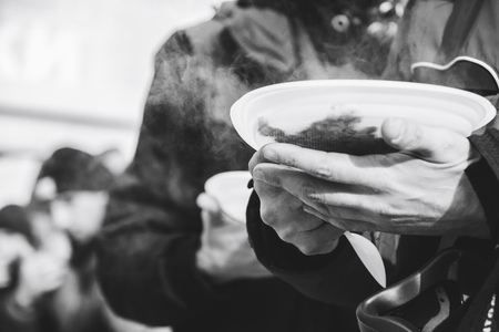 Homeless man holding a bowl of foodの写真素材