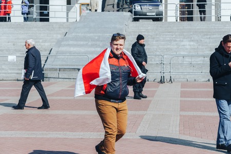 Minsk, Belarus. March 25, 2018 A holiday dedicated to the 100th anniversary of the founding of the Belarusian People's Republic A guy wrapped in a flag goes outdoorsのeditorial素材