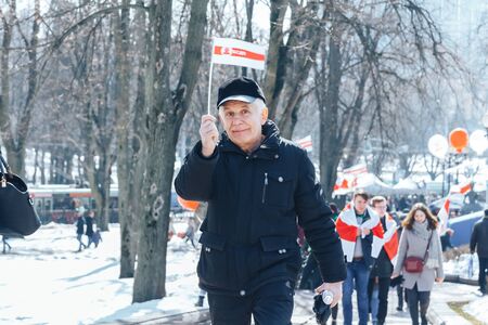 Minsk, Belarus. March 25, 2018 A holiday dedicated to the 100th anniversary of the founding of the Belarusian People's Republic Man holding a small flag outdoorsのeditorial素材