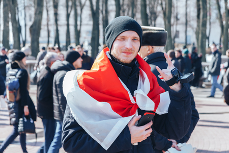 Minsk, Belarus. March 25, 2018 A holiday dedicated to the 100th anniversary of the founding of the Belarusian People's Republic A man wrapped in a flag stands on the squareのeditorial素材
