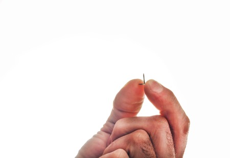 Male hand is holding a metal pushpin.