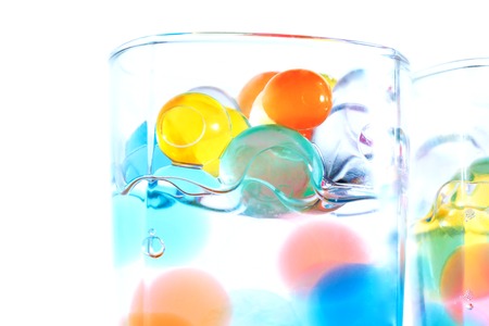 Multi-colored silicone balls lie in a glass on a white background