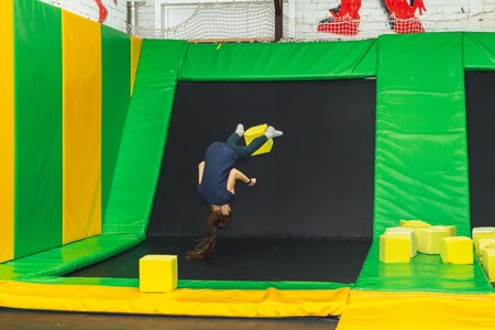 Young girl jumping with foam cube on a trampoline in the trampoline hallの写真素材