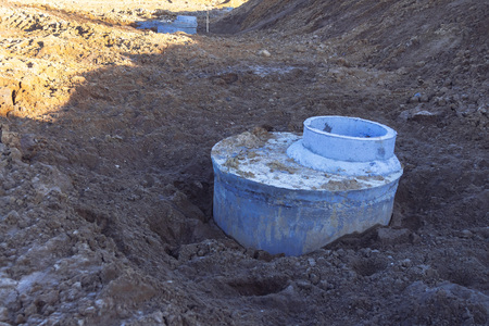 Construction site concrete well for water pipes and sewage sprinkled with earth Close up