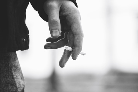 Young man's hand holding a cigarette with smoke Black and white image Close upの写真素材